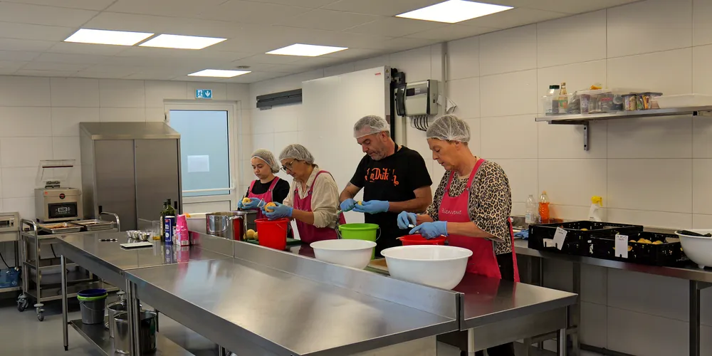 L'atelier de la conserverie : l'équipe épluche les fruits autour des plans de travail en inox
