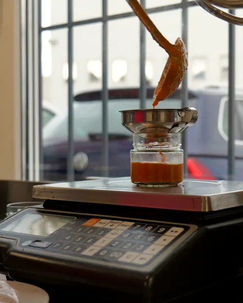 Remplissage d'un bocal de sauce posé sur une balance