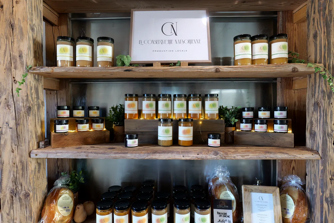 Présentoir en bois garni de bocaux de la Conserverie Naborienne, panneau « Production locale »